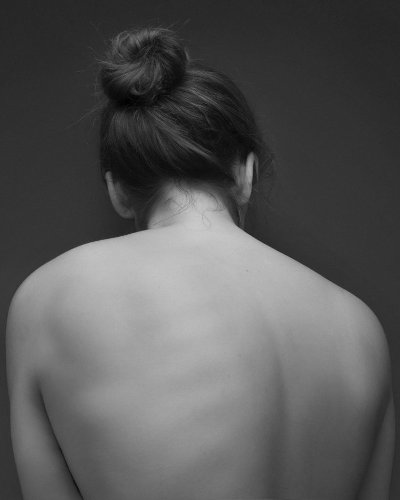 Black and white photograph of a naked woman's back.